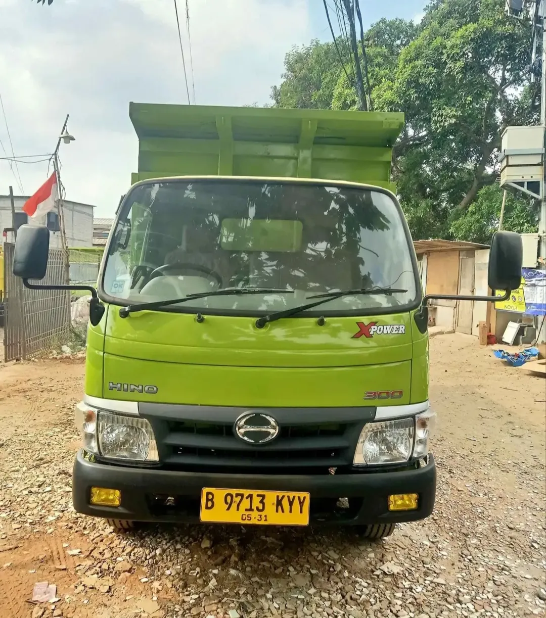 Dump truck Hino 300 berwarna hijau tampak depan.