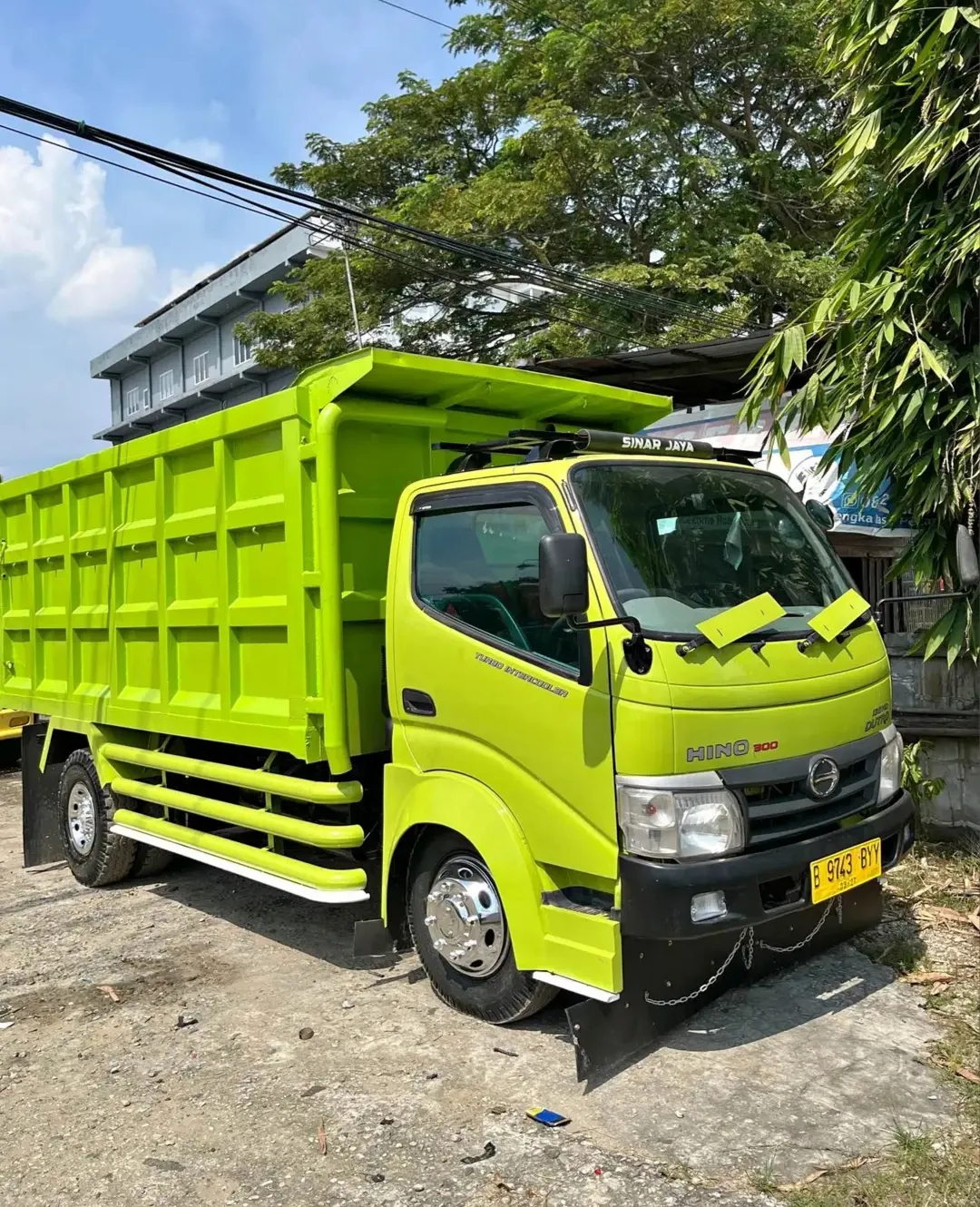 Dump truck Hino 300 berwarna hijau limau tampak dari sisi depan.