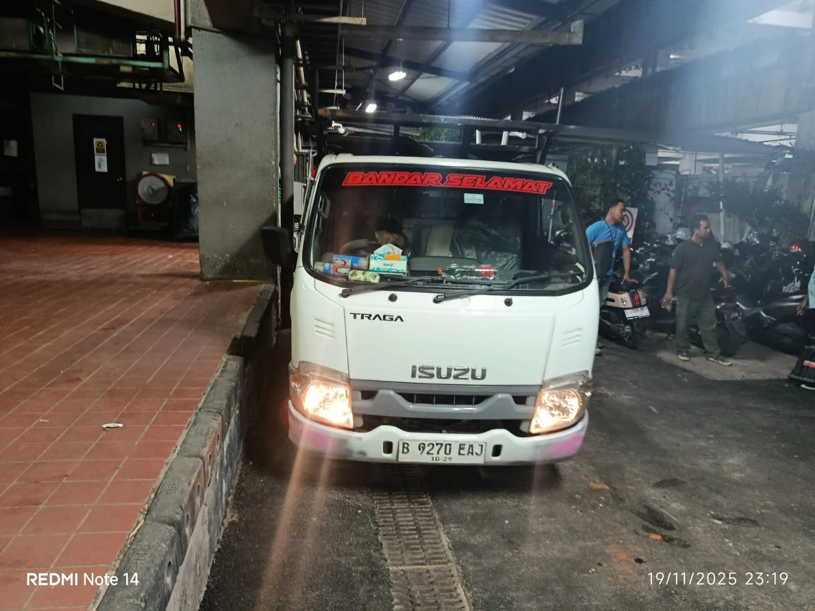 Armada Isuzu Traga putih berada di lokasi pelanggan pada malam hari.