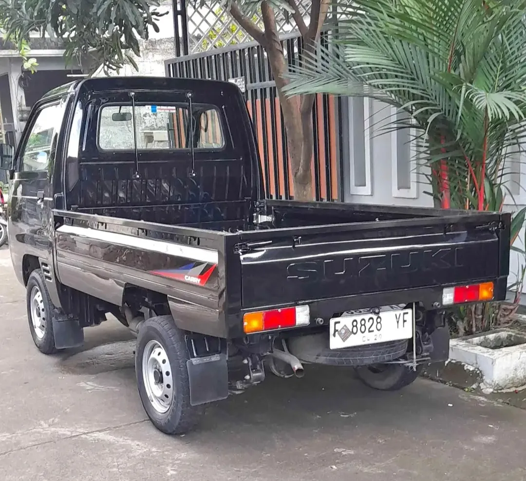 Armada pickup Suzuki Carry hitam tampak dari sisi belakang.