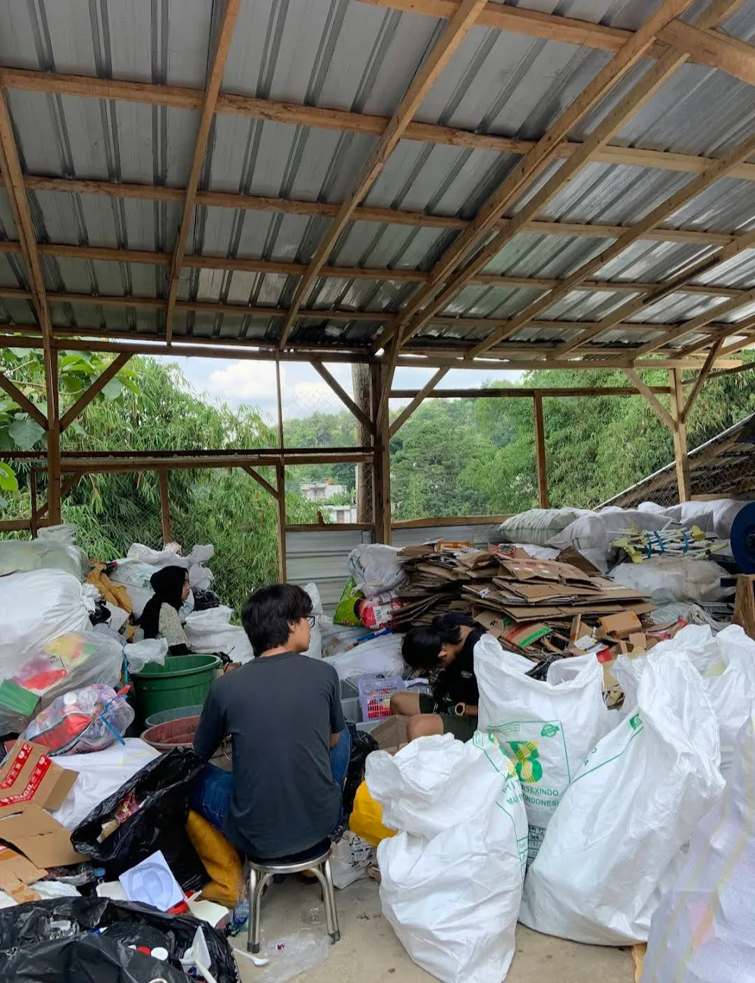 Petugas memilah sampah anorganik secara manual di area beratap.