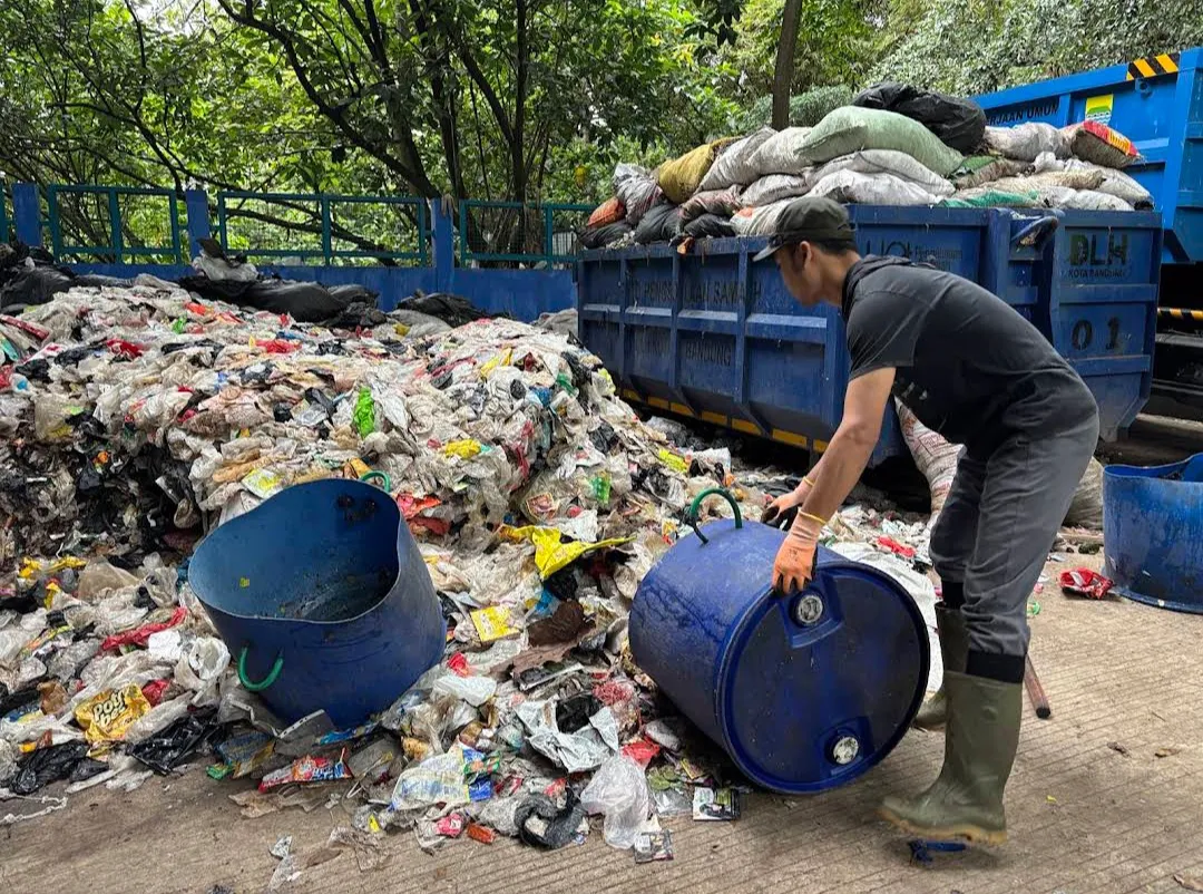 Petugas menangani material plastik di area pemilahan sampah.